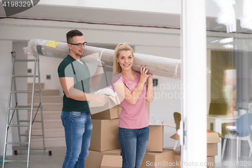 Image of couple carrying a carpet moving in to new home