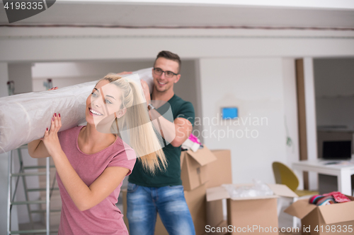 Image of couple carrying a carpet moving in to new home