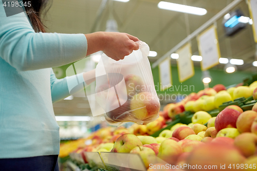 Image of woman with bag buying apples at grocery store