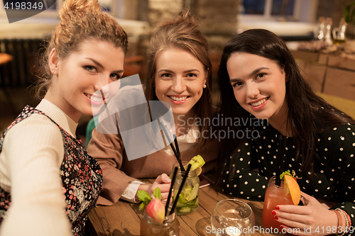 Image of happy friends with drinks taking selfie at cafe