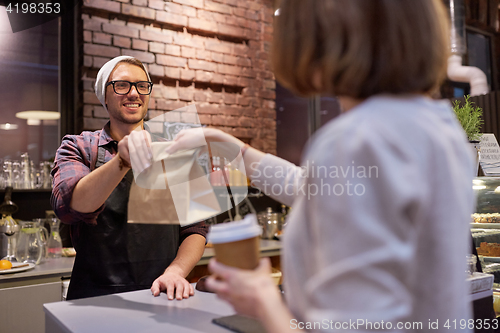 Image of woman taking paper bag from seller at cafe