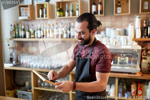 Image of happy man or waiter with chalkboard banner at bar