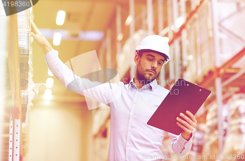 Image of happy businessman with clipboard at warehouse