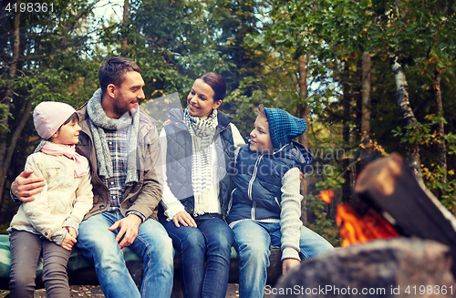 Image of happy family sitting on bench at camp fire