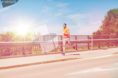 Image of smiling young man running at summer seaside