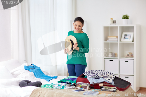 Image of woman packing travel bag at home or hotel room