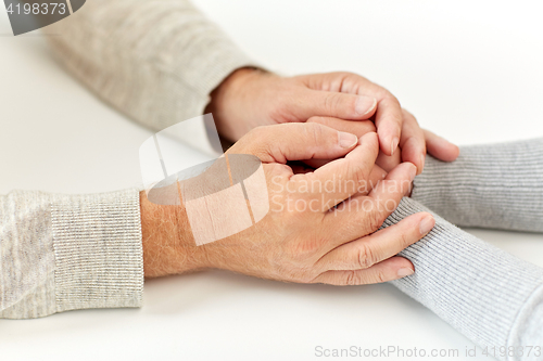 Image of close up of old man and young woman holding hands