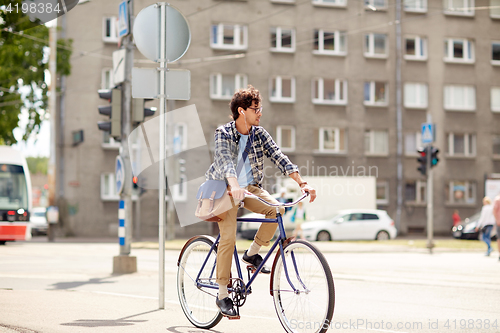 Image of young hipster man with bag riding fixed gear bike