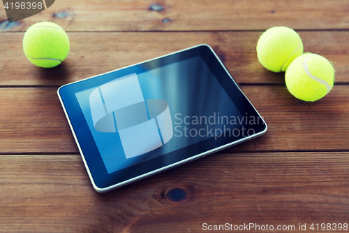 Image of close up of tennis balls and tablet pc on wood