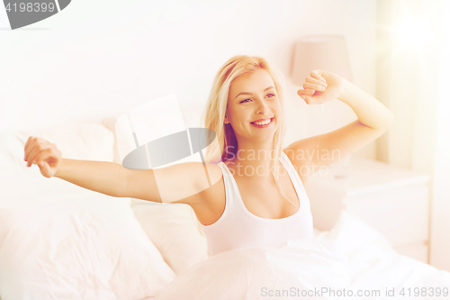 Image of young woman stretching in bed after waking up