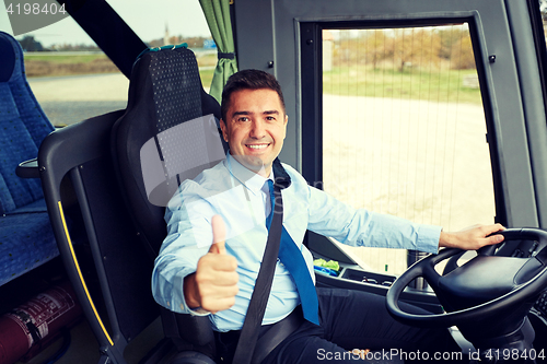 Image of happy driver driving bus and snowing thumbs up