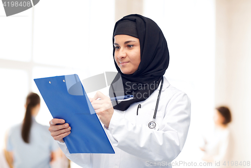 Image of muslim female doctor in hijab with clipboard