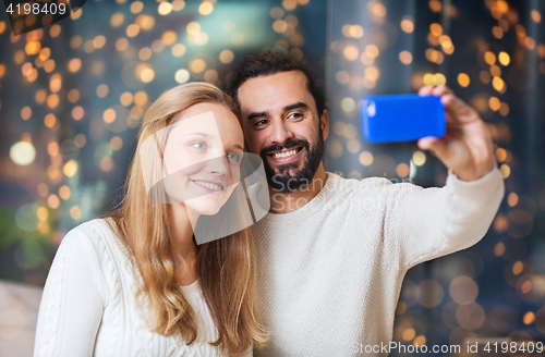 Image of happy couple with smartphone taking selfie