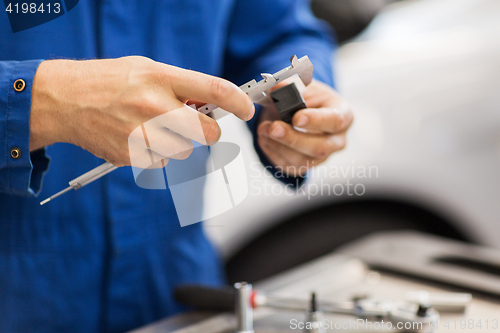 Image of mechanic with calipers measures detail at workshop