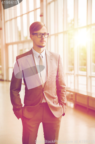 Image of young businessman in suit and glasses at office