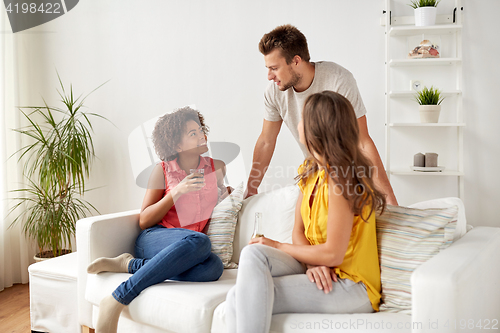 Image of group of happy friends with drinks talking at home