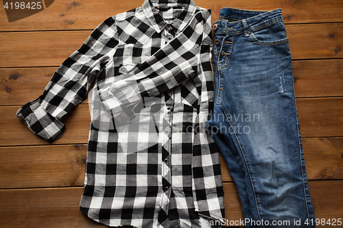 Image of close up of checkered shirt and jeans on wood