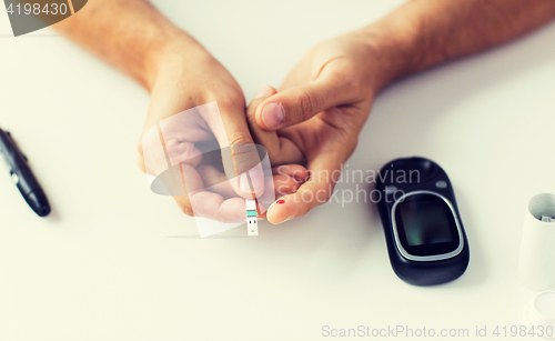 Image of close up of man checking blood sugar by glucometer