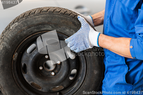 Image of mechanic with wheel tire at car workshop