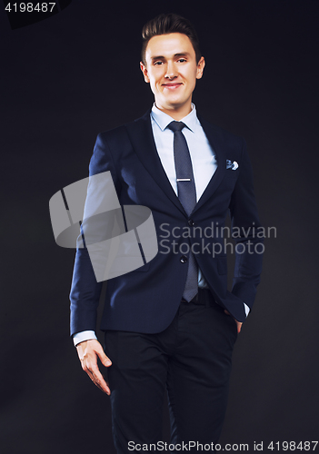 Image of young pretty business man standing on black background, modern h