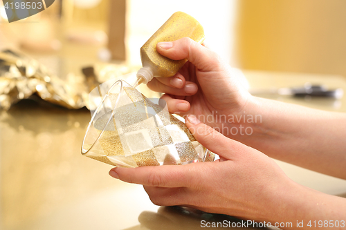 Image of Woman decorates glass candlestick 