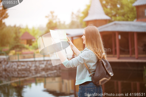 Image of Traveler girl searching right direction on map, orange sunset light, traveling along Europe