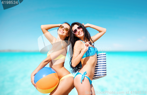 Image of happy young women in bikini posing on summer beach