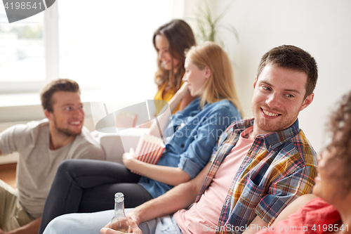 Image of happy friends with popcorn and beer at home