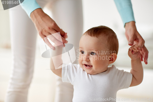 Image of happy baby learning to walk with mother help