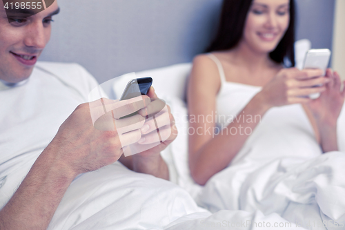 Image of close up of smiling couple in bed with smartphones