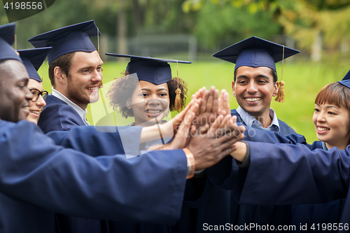 Image of happy students in mortar boards making high five