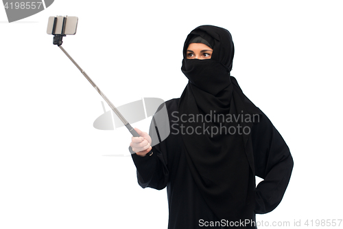 Image of muslim woman in hijab taking selfie by smartphone