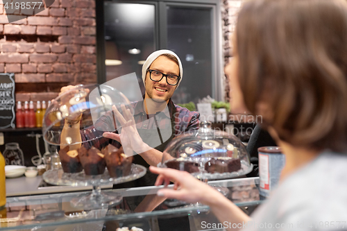 Image of man or barman with cakes serving customer at cafe