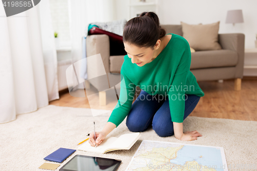 Image of woman with notebook and travel map at home