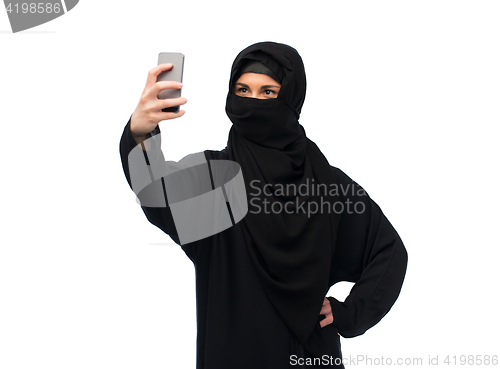 Image of muslim woman in hijab taking selfie by smartphone