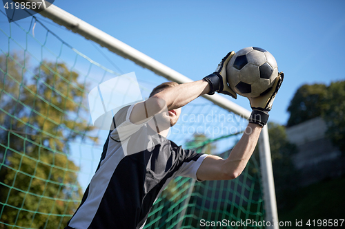 Image of goalkeeper with ball at football goal on field