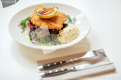 Image of close up of fish salad with roasted lemon on plate