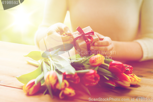 Image of close up of woman with gift box and tulip flowers