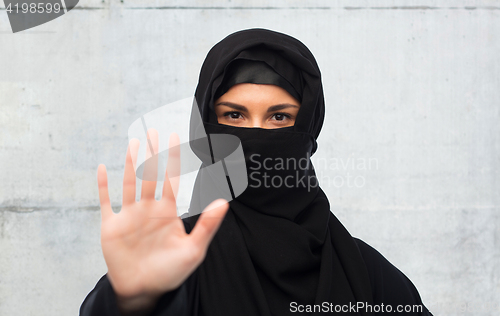 Image of muslim woman in hijab showing stop sign