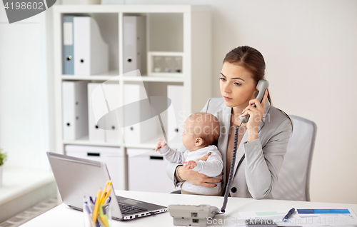 Image of businesswoman with baby calling on phone at office