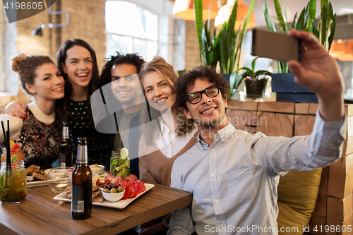 Image of friends taking selfie by smartphone at bar or cafe