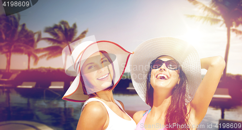 Image of smiling young women in hats on beach