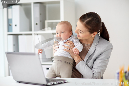 Image of happy businesswoman with baby and laptop at office