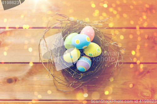 Image of close up of colored easter eggs in nest on wood