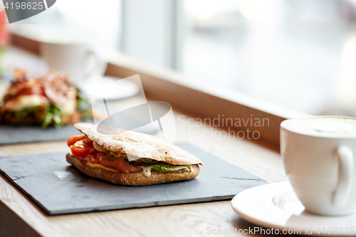 Image of salmon panini sandwich on stone plate at cafe