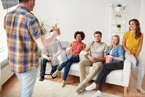 Image of friends with popcorn and drinks talking at home