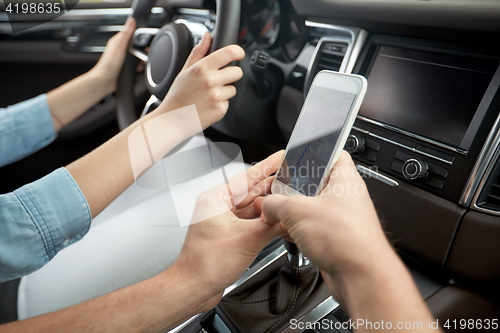 Image of happy man and woman with smartphone driving in car