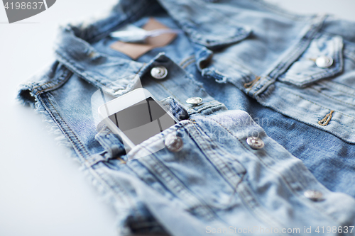 Image of smartphone in pocket of denim jacket or waistcoat