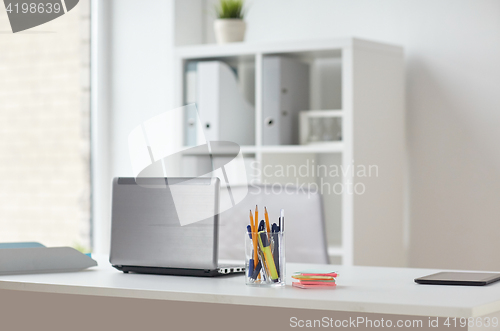 Image of laptop with pen and stickers on office table