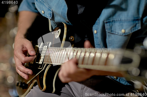 Image of close up of man playing guitar at studio rehearsal